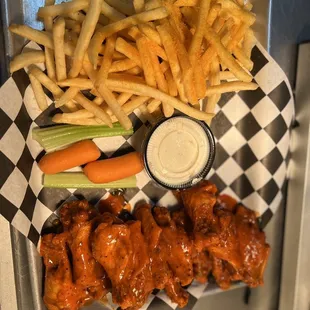 a tray of chicken wings, carrots, and fries