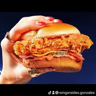 a hand holding a chicken sandwich