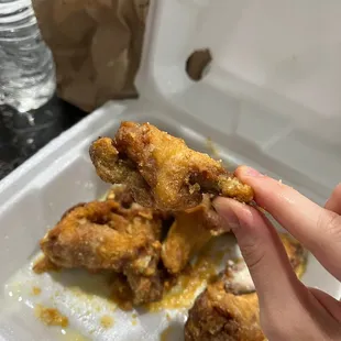 a hand holding a piece of fried chicken