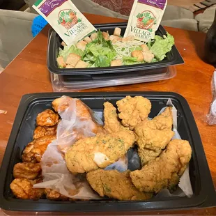 two trays of fried chicken and a salad