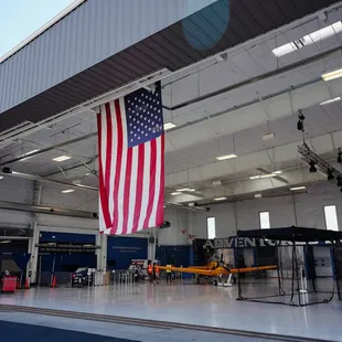 The back of the Wings Over the Rockies Exploration of Flight hangar. There is an American flag hanging from the ceiling.