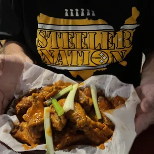 a man holding a basket of wings
