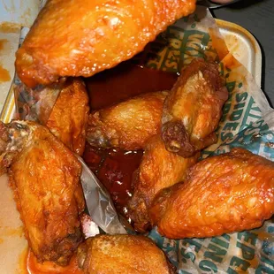 a person grabbing a piece of chicken wings