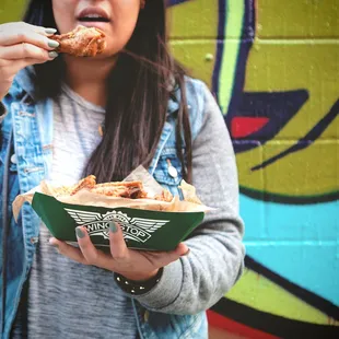 a woman eating food in front of a graffiti wall