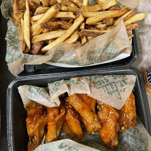 two trays of chicken wings and french fries