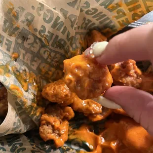 a hand picking up a piece of food from a wrapper