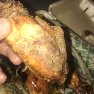 a hand holding a piece of fried chicken