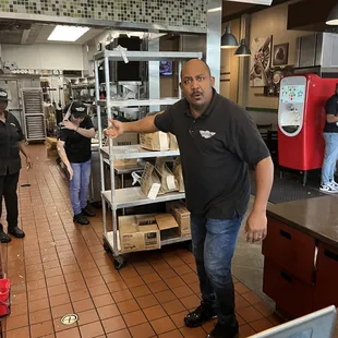 a man in a black shirt standing in a kitchen