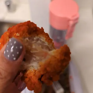 a hand holding a half eaten fried chicken