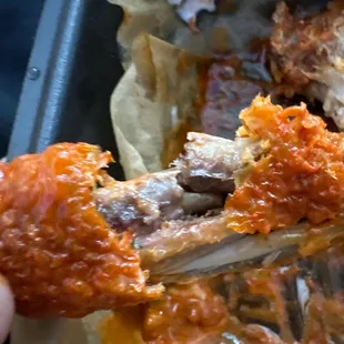 a hand holding a piece of meat with sauce on it
