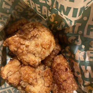 a basket of fried chicken in a paper wrapper