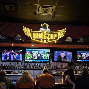 people sitting at a bar watching tvs