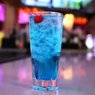 a blue drink with a cherry in it