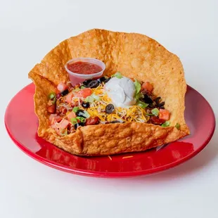 a taco bowl with tortilla and sour cream