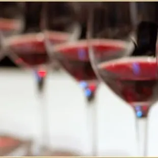 a row of wine glasses filled with red wine