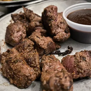 a plate of meat and a bowl of sauce
