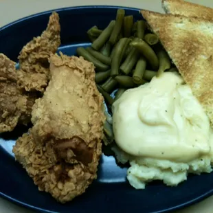 a plate of fried chicken, mashed potatoes, green beans and mashed potatoes