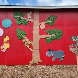 a red barn with a painted mural of a tree and animals