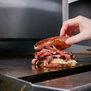 a person putting a sandwich on a bun