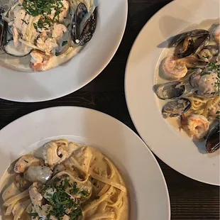 three plates of pasta and seafood