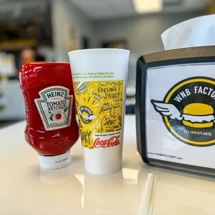 a cup of ketchup and a bottle of ketchup