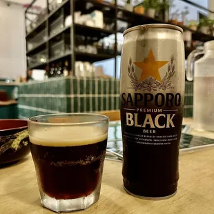 a glass of beer and a can of black ale