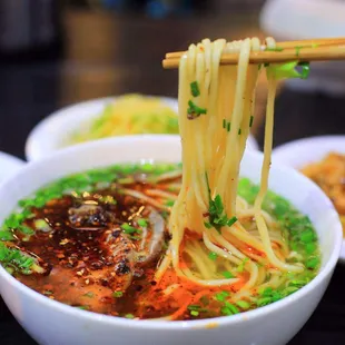 a bowl of noodles with chopsticks