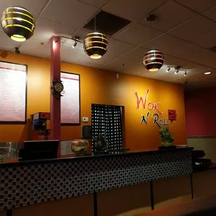 a restaurant counter with a menu on the wall