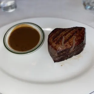 a piece of steak on a plate with a side of gravy