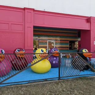 a row of rubber ducks in front of a pink building