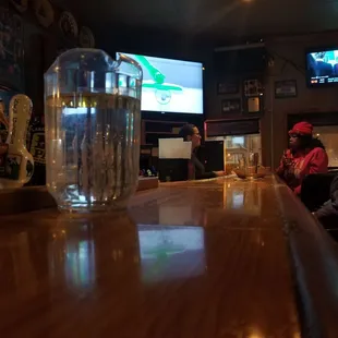 people sitting at a bar watching televisions