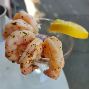 a glass of shrimp cocktail with a lemon wedge