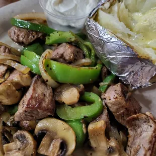 Steak tips with grilled onions,  green peppers and mushrooms with a baked potato