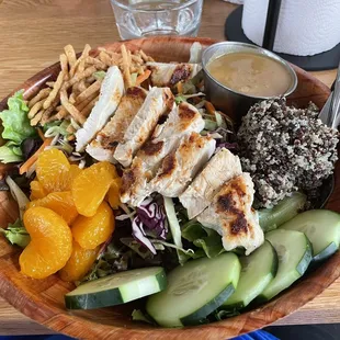 a salad with chicken, oranges, cucumbers, and french fries