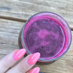 a woman's hand holding a glass of juice