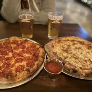 two pizzas and a beer on a table