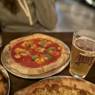 two pizzas and a beer on a table