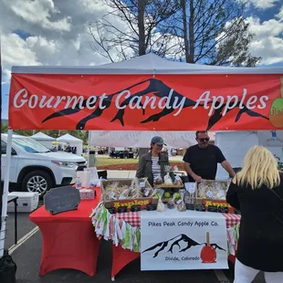 a man and a woman standing in front of an apple stand