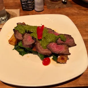 a plate of steak with green sauce