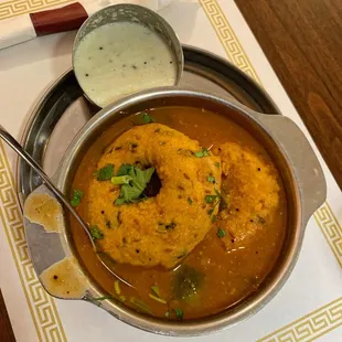 a bowl of food with a spoon and sauce