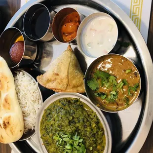 Lunch with Samosa appetizer, naan,-, Jeera rice, mango pickle, spinach and paneer curry, and lentils, Keer dessert