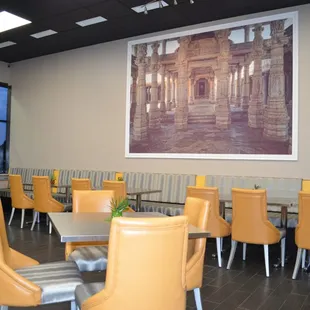 a dining area with chairs, tables, and a picture on the wall