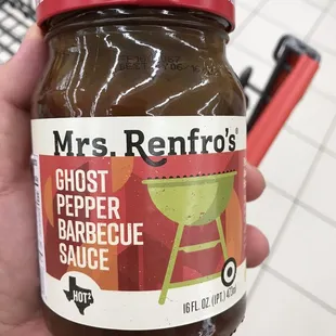 a hand holding a jar of pepper barbecue sauce