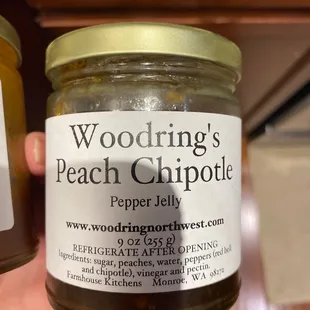 a person holding a jar of pepper jelly