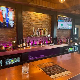 a bar with a television and wine glasses