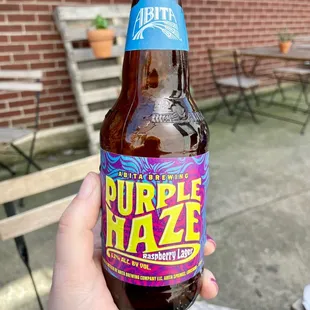 a person holding a bottle of purple haze