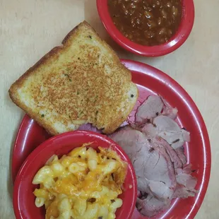 Sliced pork lunch plate with bbq beans and mac &amp; cheese.