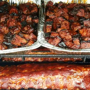 two trays of ribs on a grill