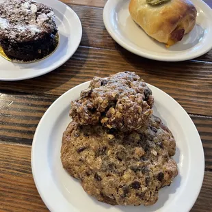 Harvest Oatmeal Raisin cookie (chewy and bready) sitting on top of the larger Rocky Mountain Chocolate Chip cookie (oats, pecans)