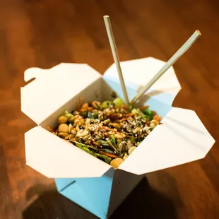 a take out box of food with chopsticks